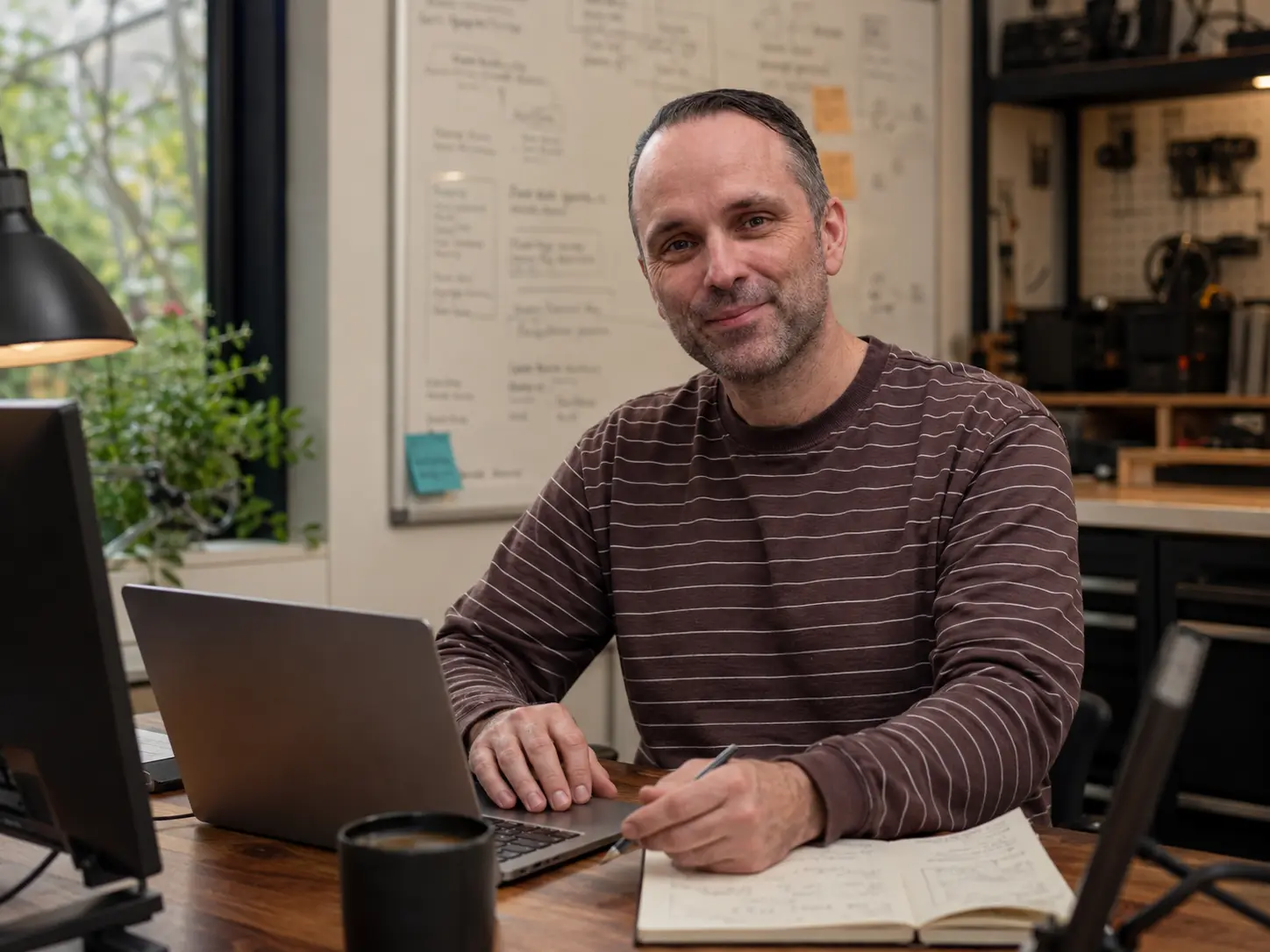 Founder reviewing an early product interface on a laptop, sketched screen flows pinned behind